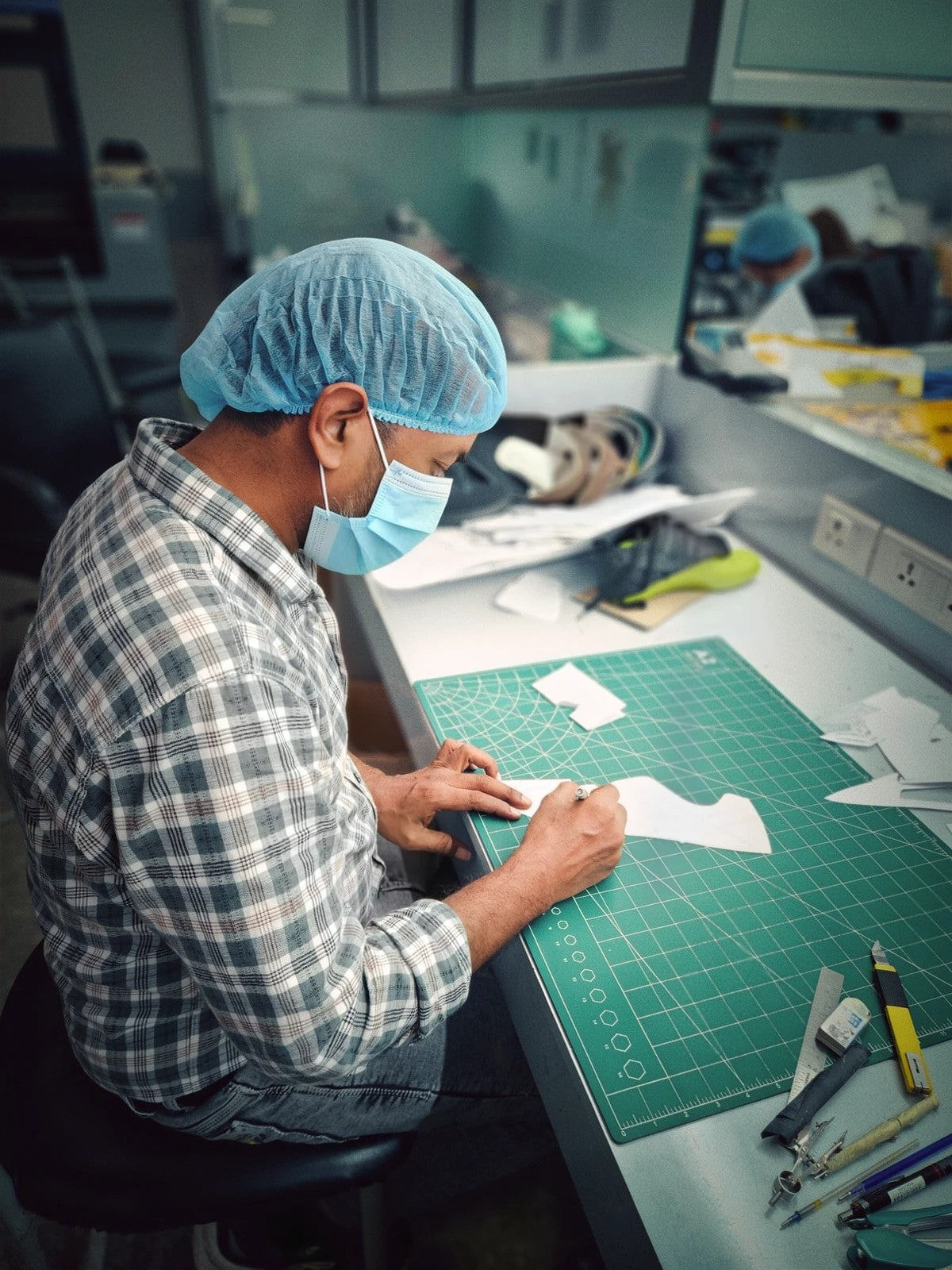 Pattern maker cutting paper templates for a new shoe